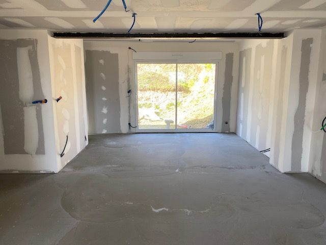 Une pièce de vie en travaux avec les fils électriques au niveau des murs et du plafond.
