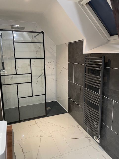 Salle de bains avec une douche à l'italienne, la paroi en verre et un sèche-serviettes.