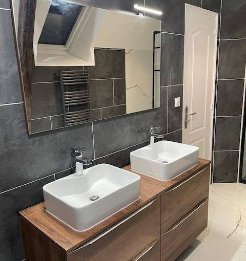 Une salle de bains avec deux vasques et un miroir. 