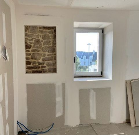 Un mur avec un détail en pierres et une fenêtre à côté. 