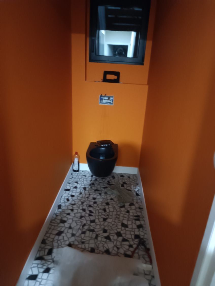 Toilettes avec les murs terracota et le carrelage au sol.