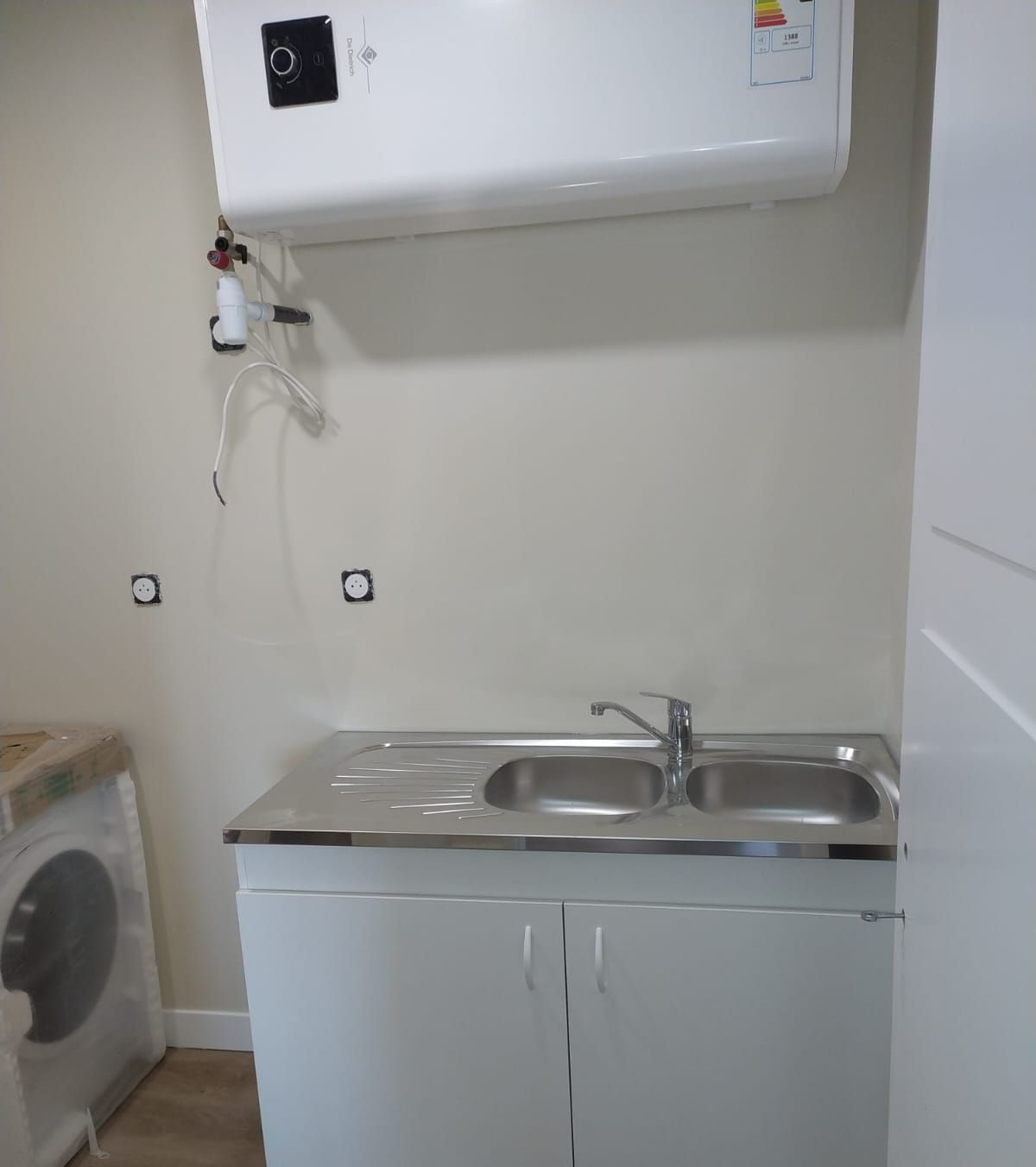 Meuble de cuisine avec un évier et un chauffe-eau au-dessus. 
