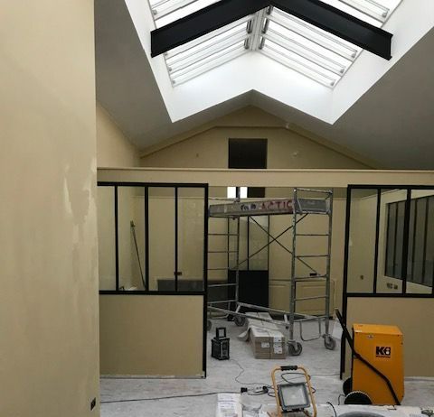 Intérieur d'un espace professionnel avec des cloisons et plafond en travaux.