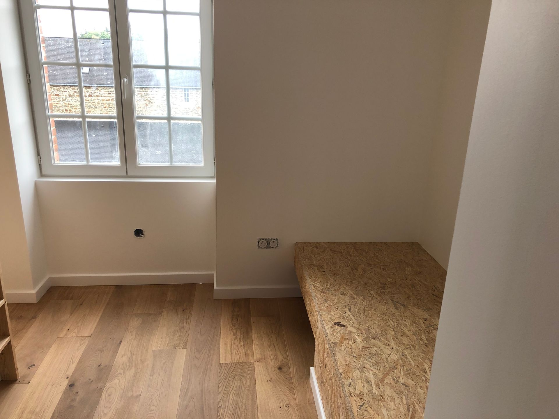 Une pièce avec un banc en panneau OSB et parquet.