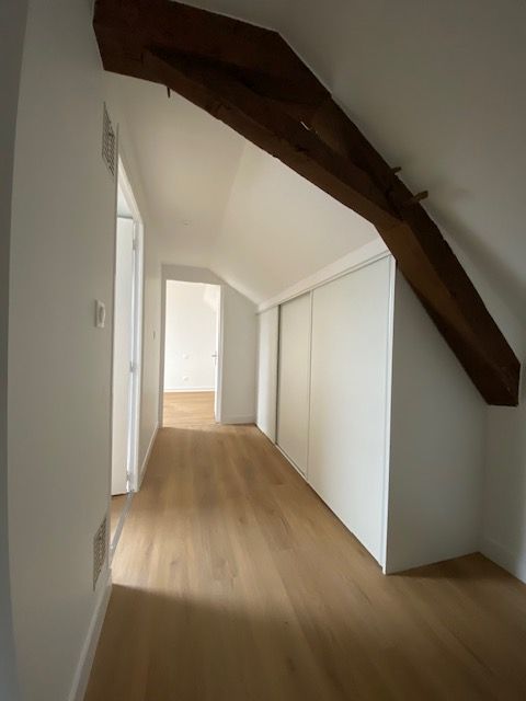 Couloir avec les murs blancs et une poutre.