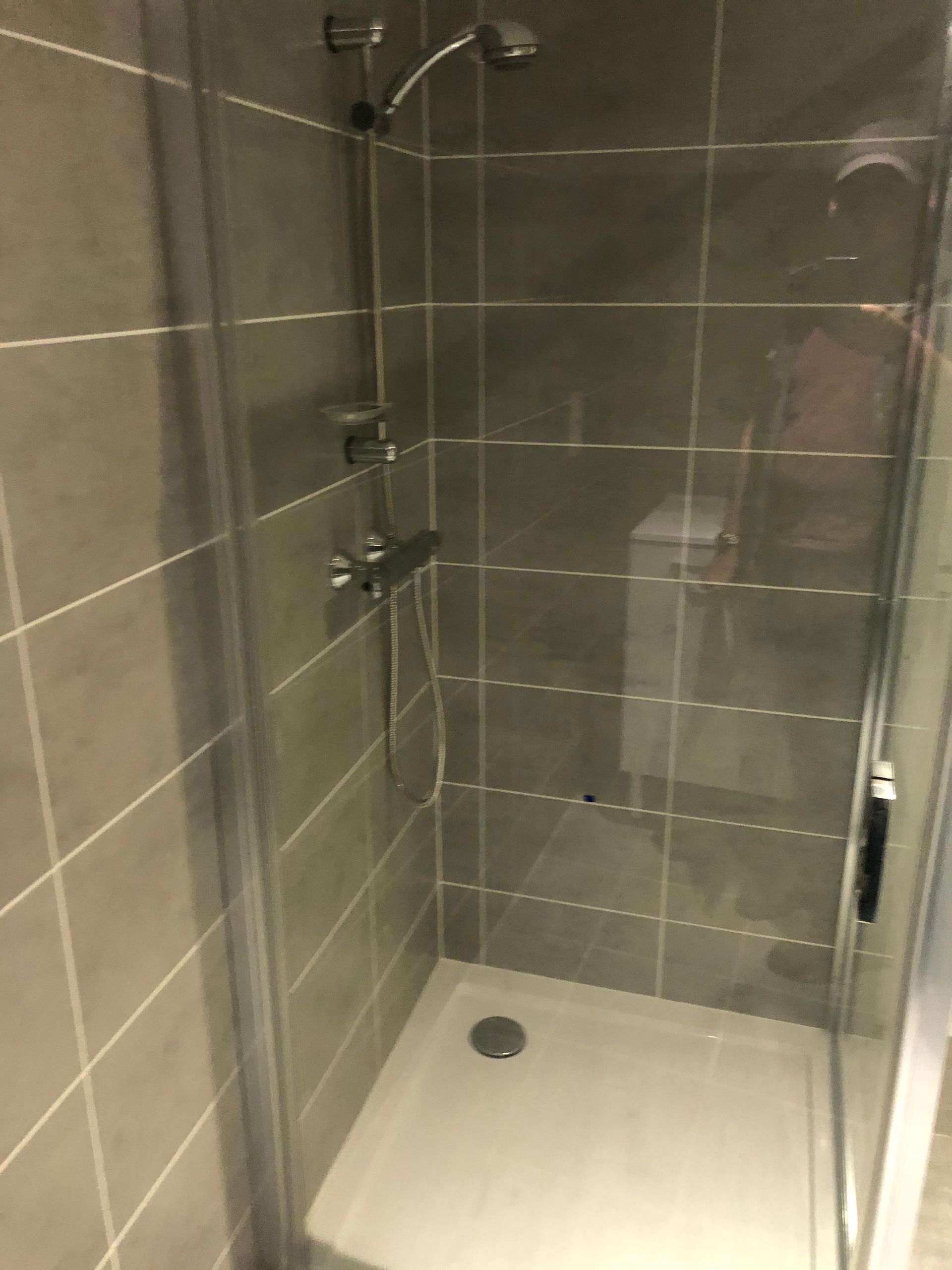 Cabine de douche avec le carrelage aux murs.