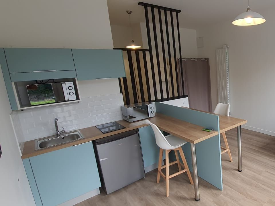 Cuisine avec les meubles bleus et une table bar.