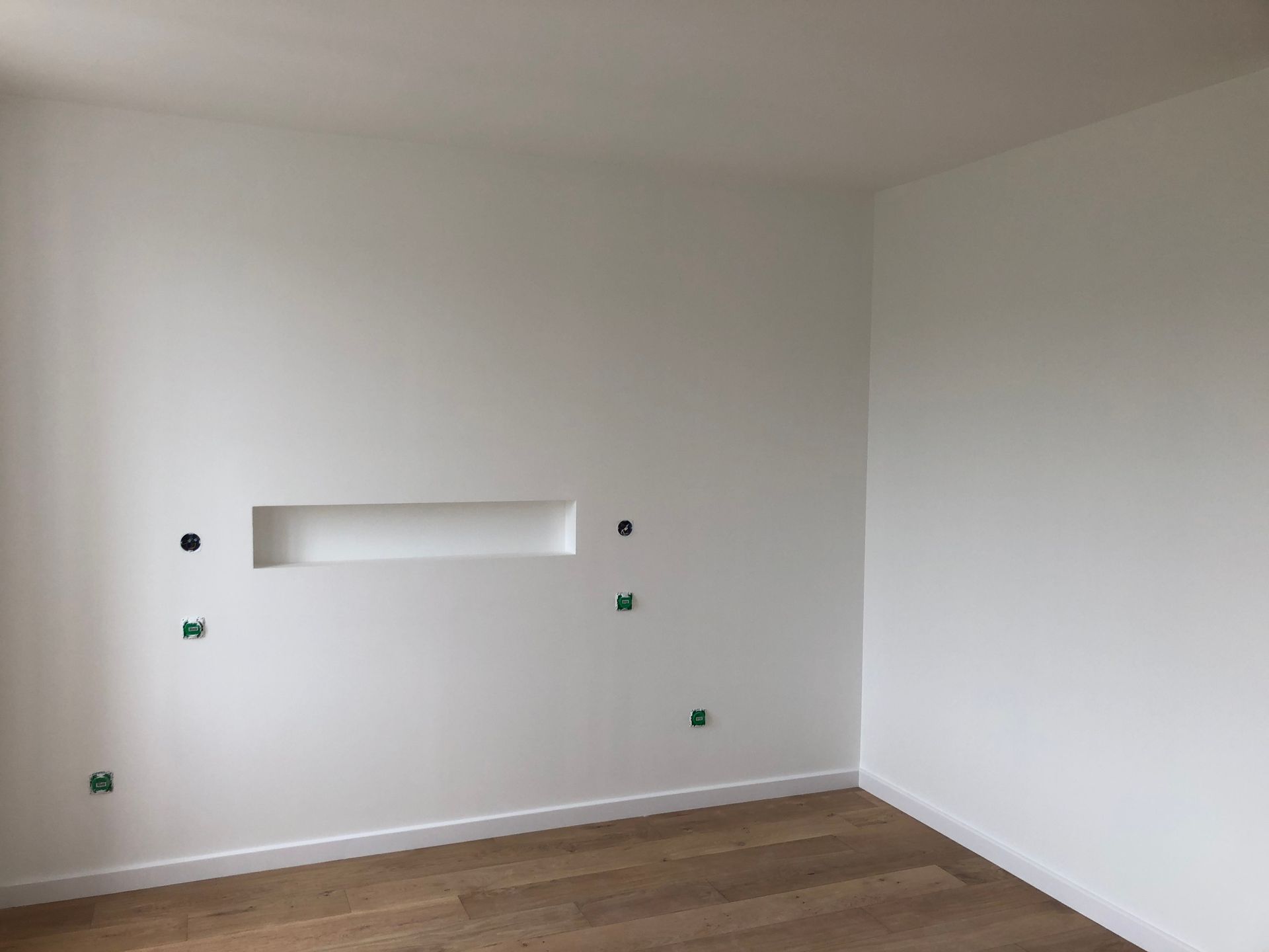 Mur blanc avec une niche et le parquet au sol.