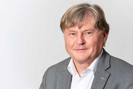 Ein Mann in Anzug und weißem Hemd schaut in die Kamera.
