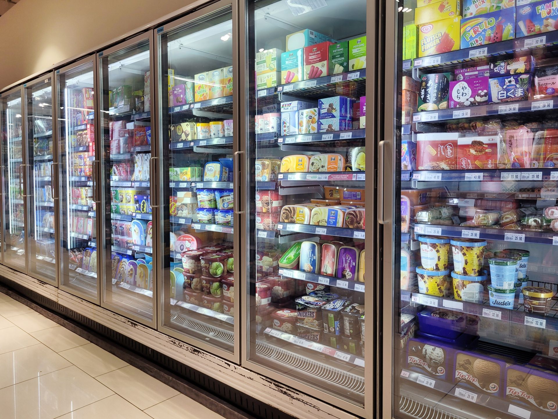 Vitrinas refrigeradas en un pasillo de supermercado, llenas de productos alimenticios congelados, listos para ser comprados.