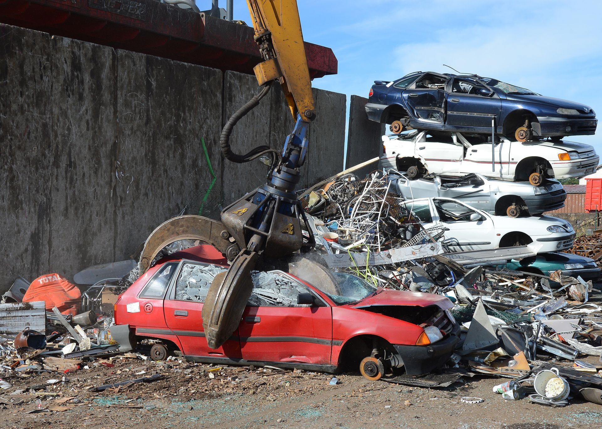 Voiture rouge en train d'être compactée par une pince