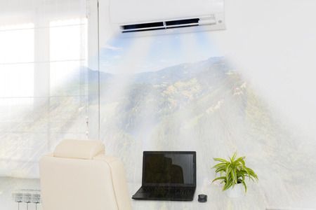 Una habitación con una computadora portátil en un escritorio y un aire acondicionado en la pared.