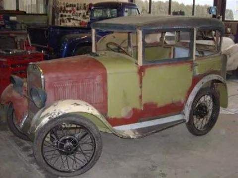 Une vieille voiture verte et rouge est garée dans un garage.