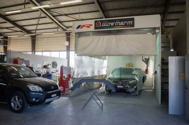 Une voiture est en train d'être peinte dans un garage.