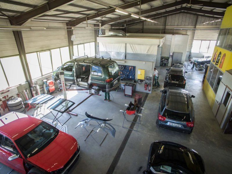 Une vue aérienne d'un atelier de réparation automobile avec une voiture rouge au milieu.