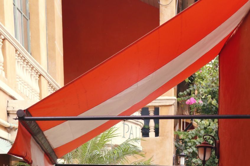 Un toldo de rayas rojas y blancas cuelga de un poste.