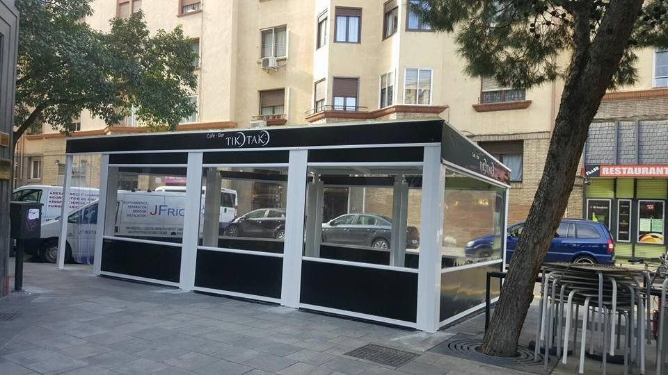 Un edificio blanco y negro con mesas y sillas delante.