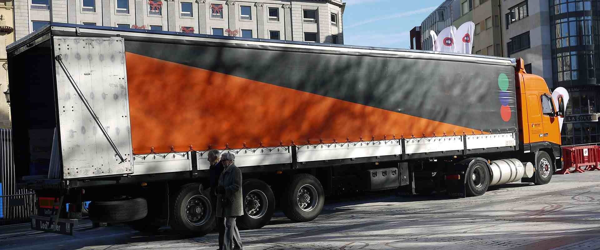 Un gran camión naranja y negro está estacionado frente a un edificio.