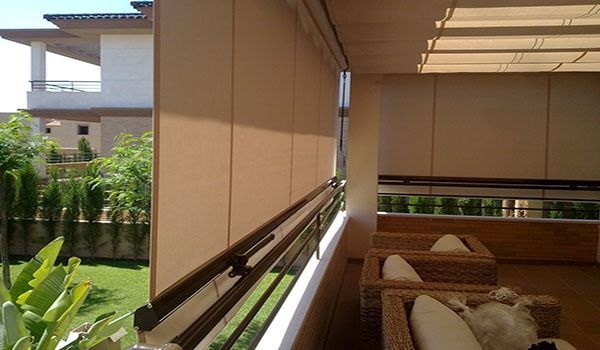 Un balcón con muebles de mimbre y una casa al fondo.