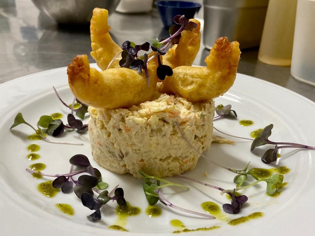 Un plato blanco cubierto con ensalada de cangrejo y camarones fritos.