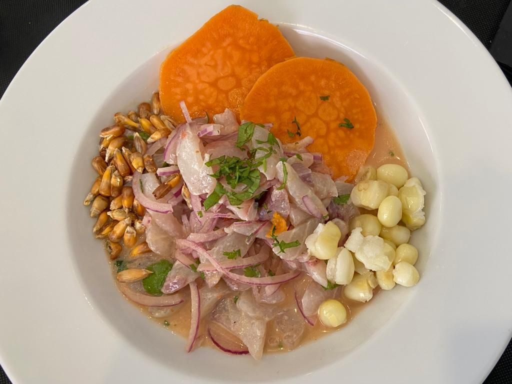 Un plato blanco cubierto con una ensalada de cebollas, maíz y zanahorias.