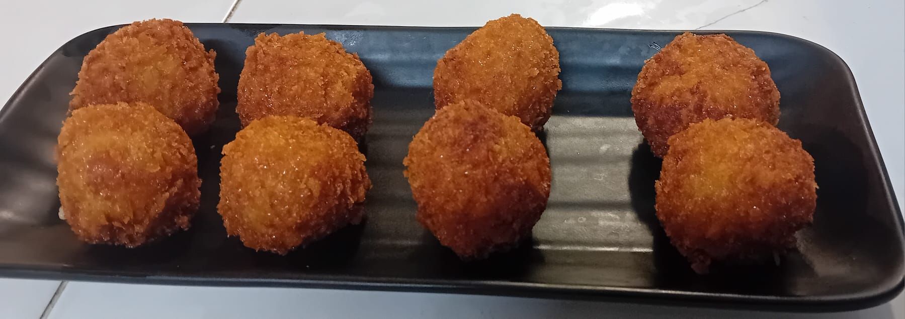 Una bandeja de bolas de comida frita sobre una mesa