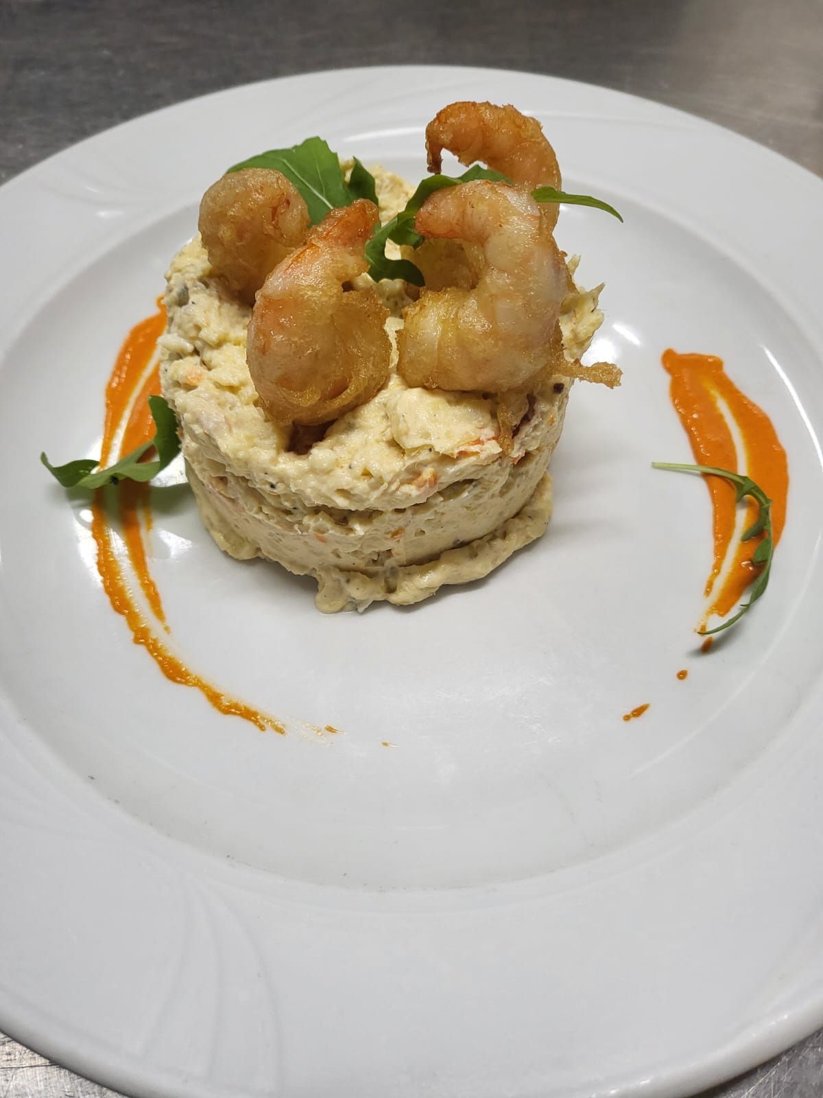 Un plato blanco cubierto con camarones y salsa sobre una mesa.