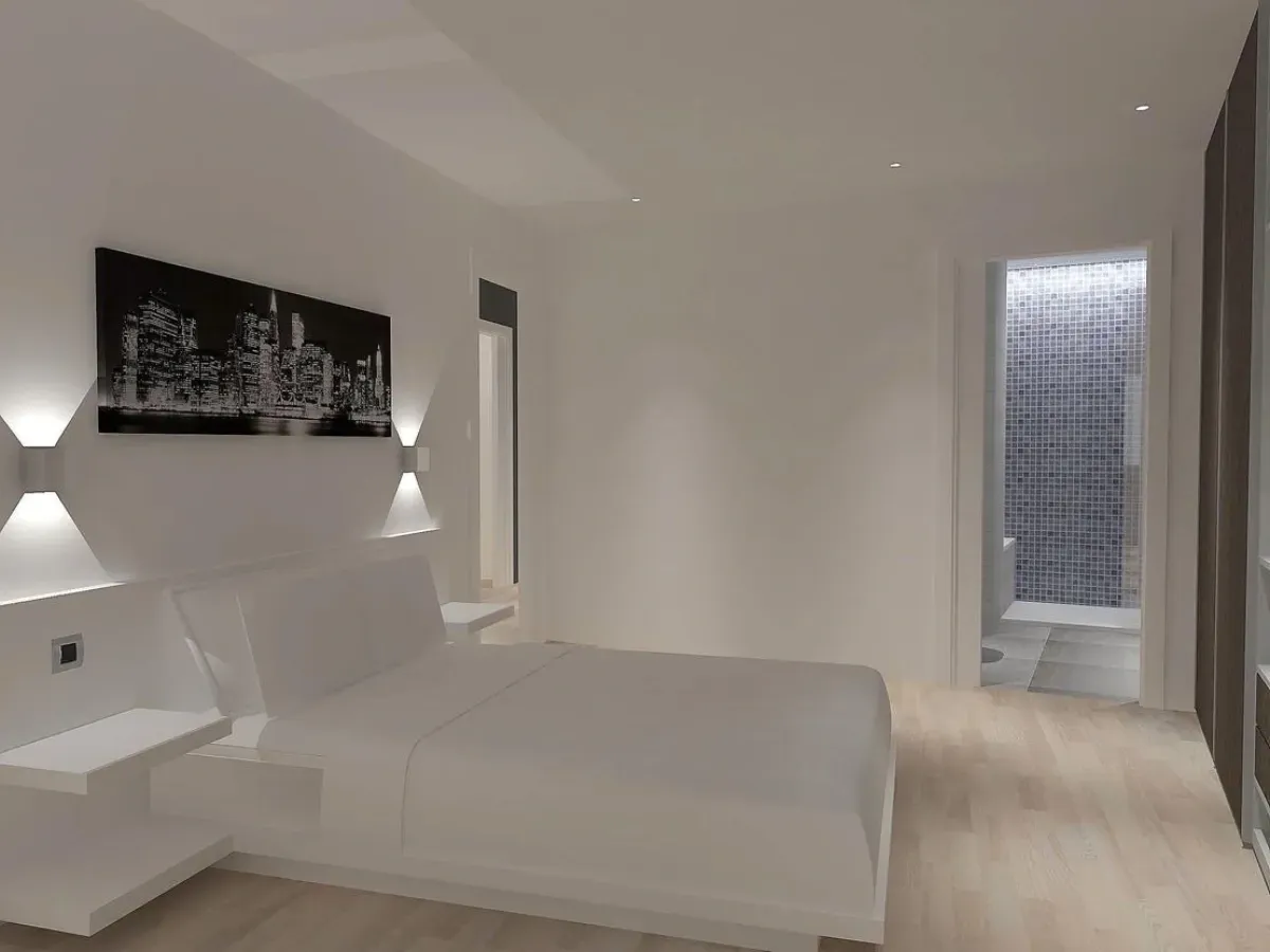 Un dormitorio minimalista con una cama blanca, mesitas de noche flotantes, apliques de pared