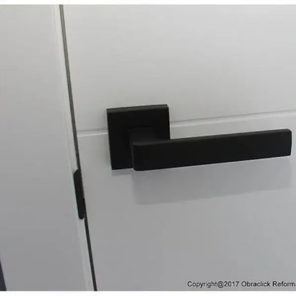 Un tirador de puerta moderno de color negro mate montado sobre una puerta interior blanca y limpia.