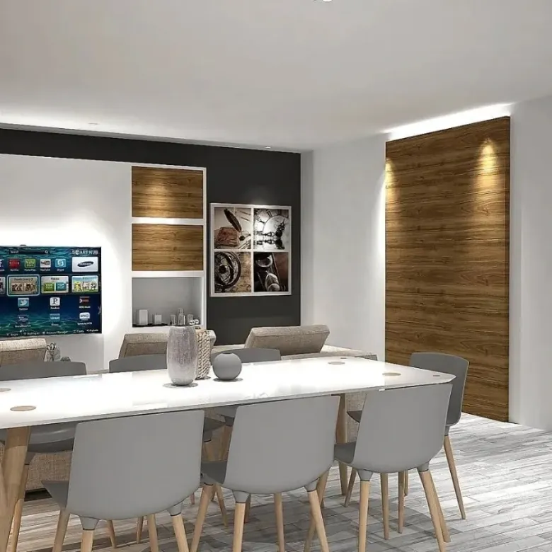 Comedor moderno con una mesa larga blanca, sillas grises, un televisor montado en la pared