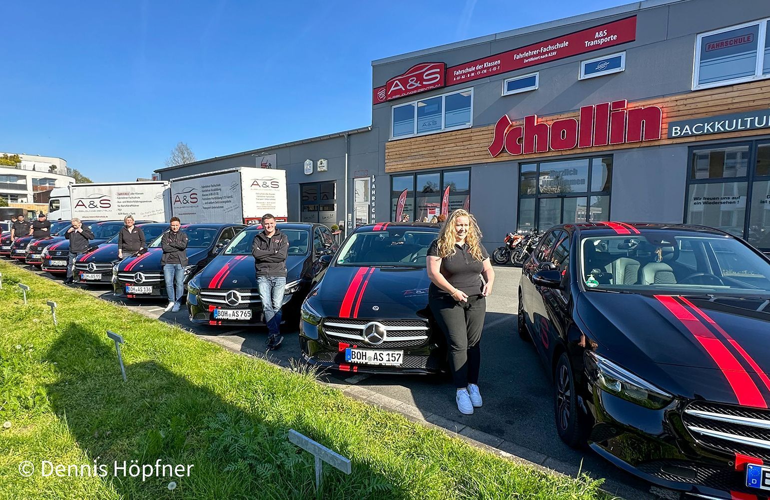 Eine Frau steht vor einer Reihe schwarzer Autos.