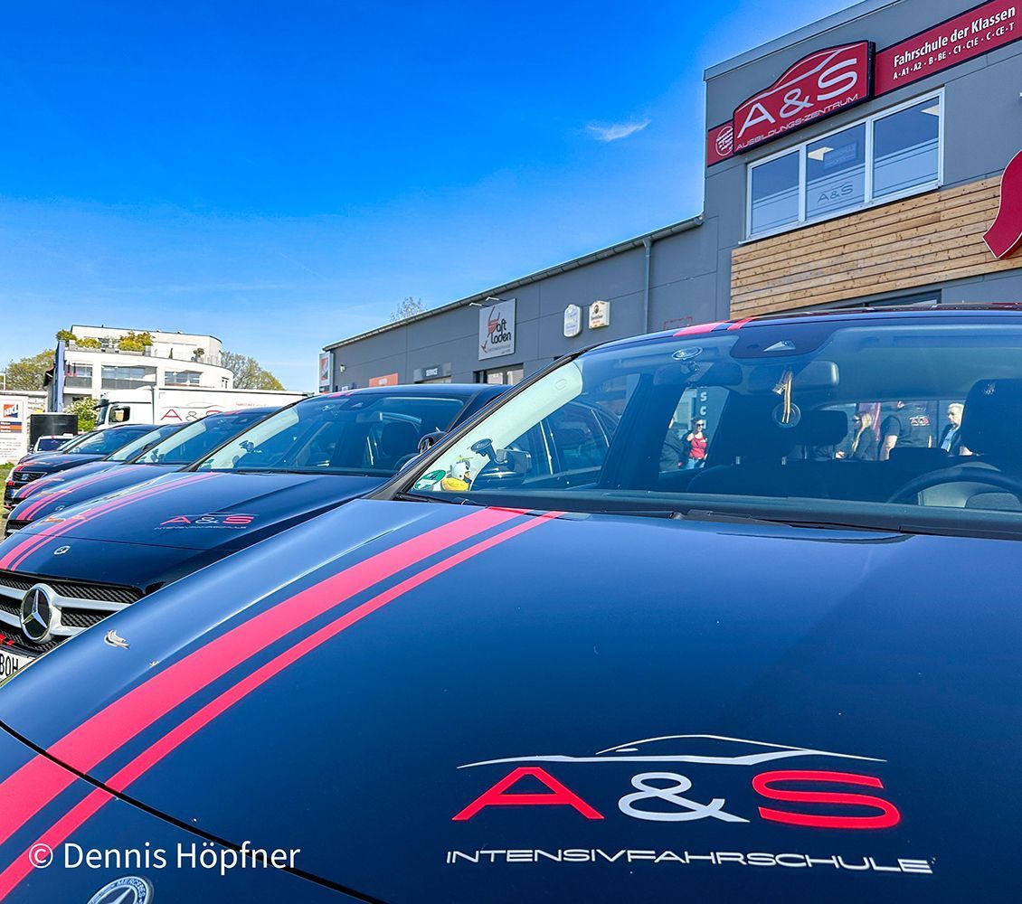 Vor einem Gebäude parkt eine Reihe schwarzer Autos.