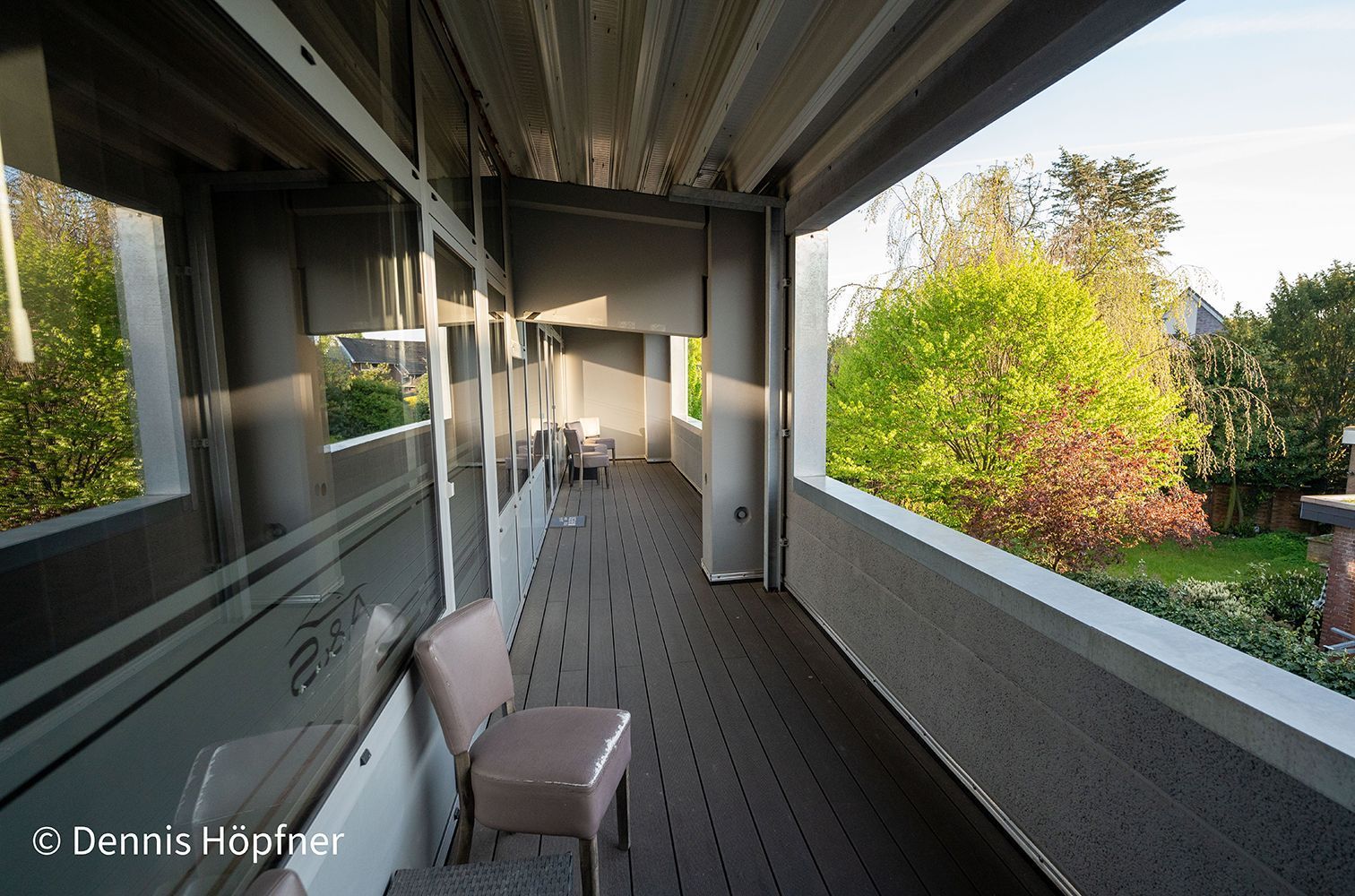 Ein langer Flur mit einem Stuhl und Bäumen im Hintergrund