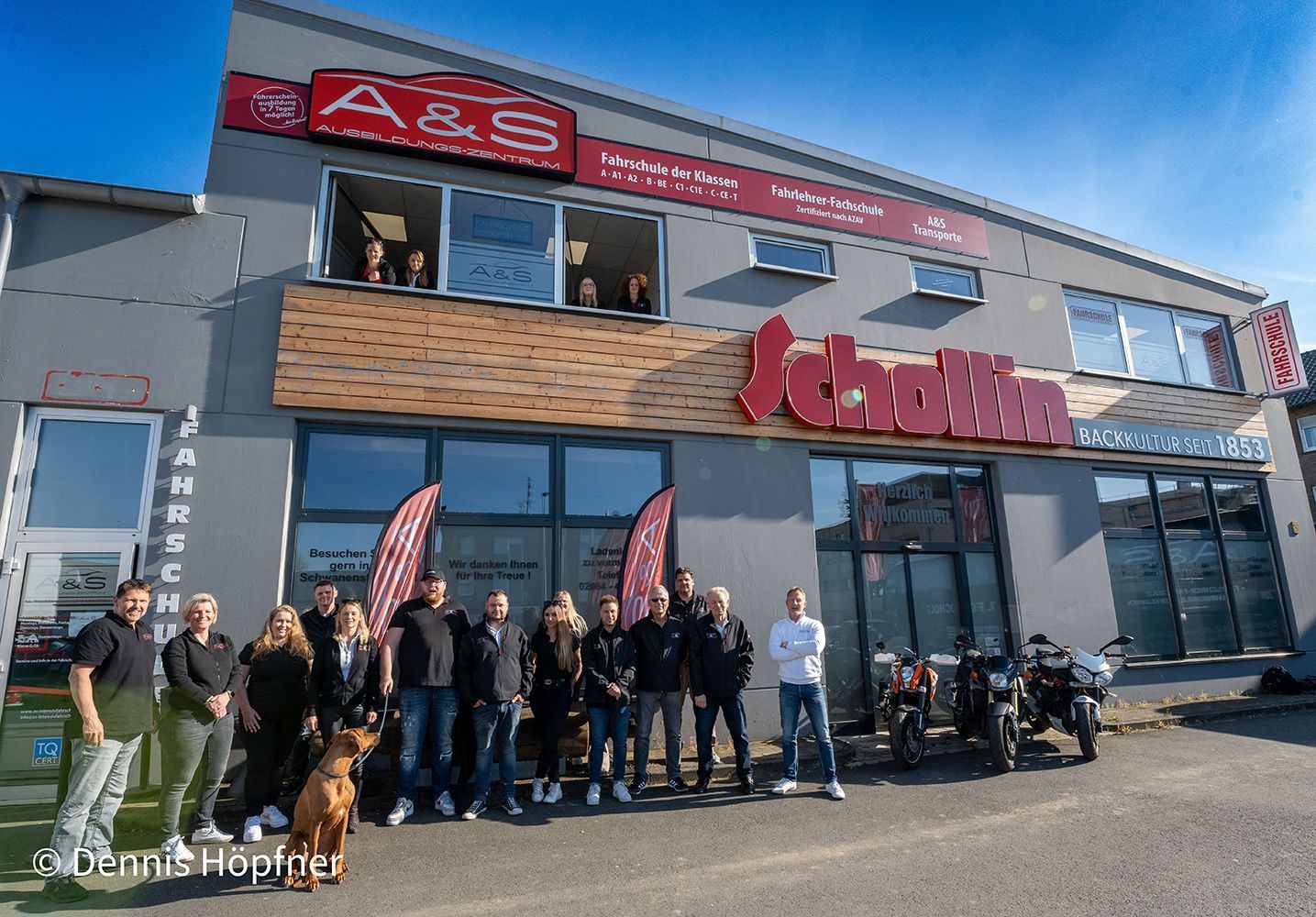 Eine Gruppe von Menschen posiert vor einem Gebäude für ein Foto.