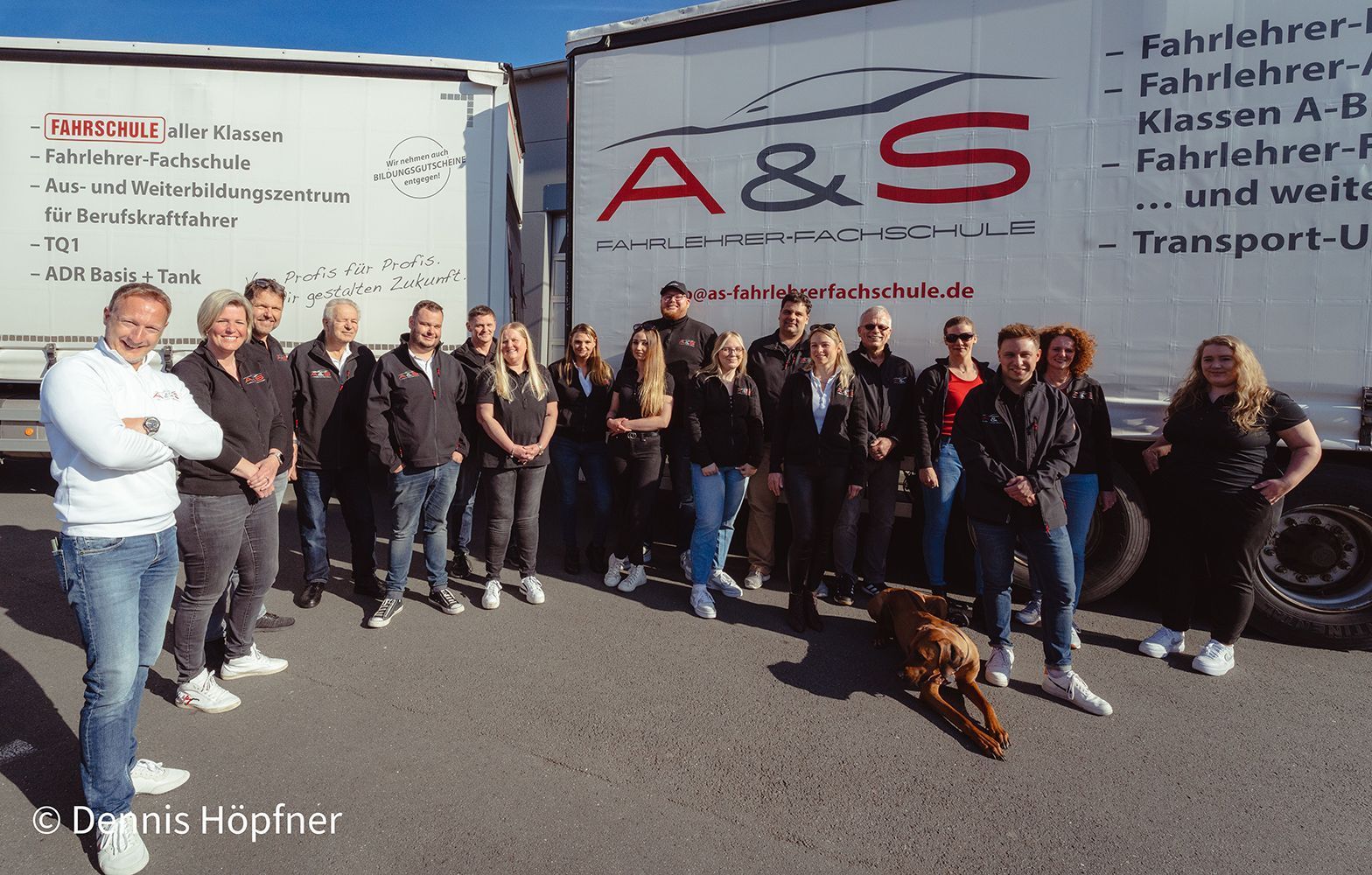 Eine Gruppe von Menschen steht vor einem LKW mit der Aufschrift A & S