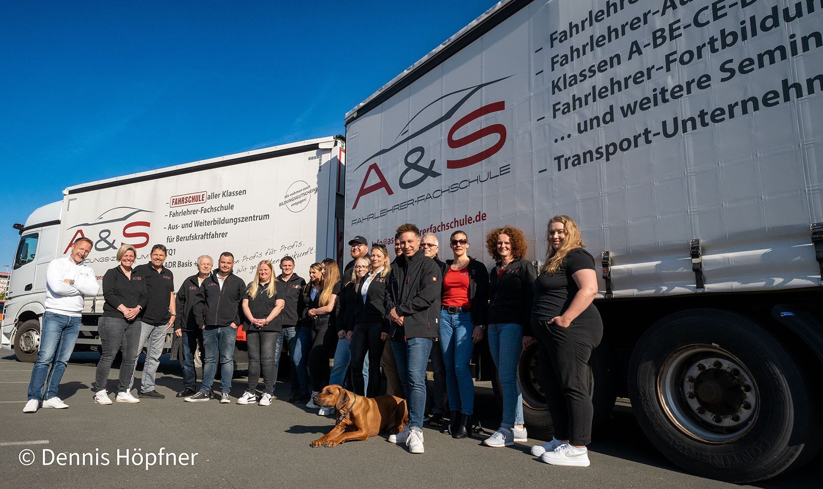 Eine Gruppe von Menschen steht vor einem LKW mit der Aufschrift A & S