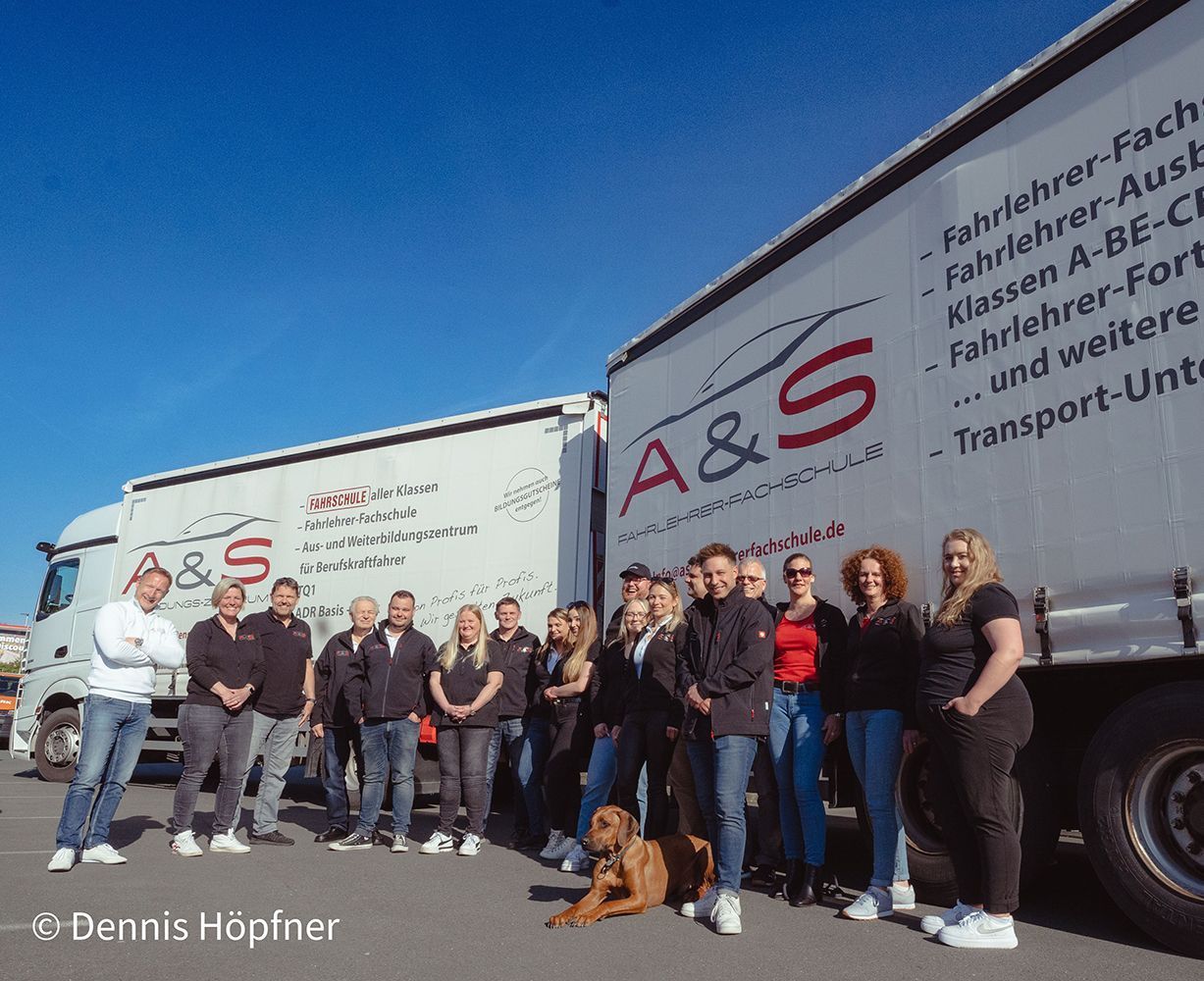 Eine Gruppe von Menschen steht vor einem LKW mit der Aufschrift A & S