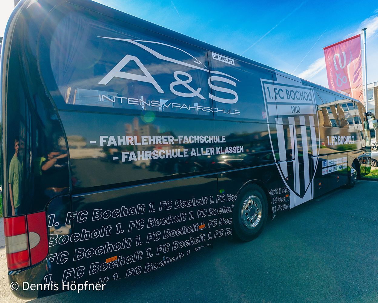 Ein schwarz-weißer Bus mit den Worten A & S auf der Seite steht am Straßenrand.