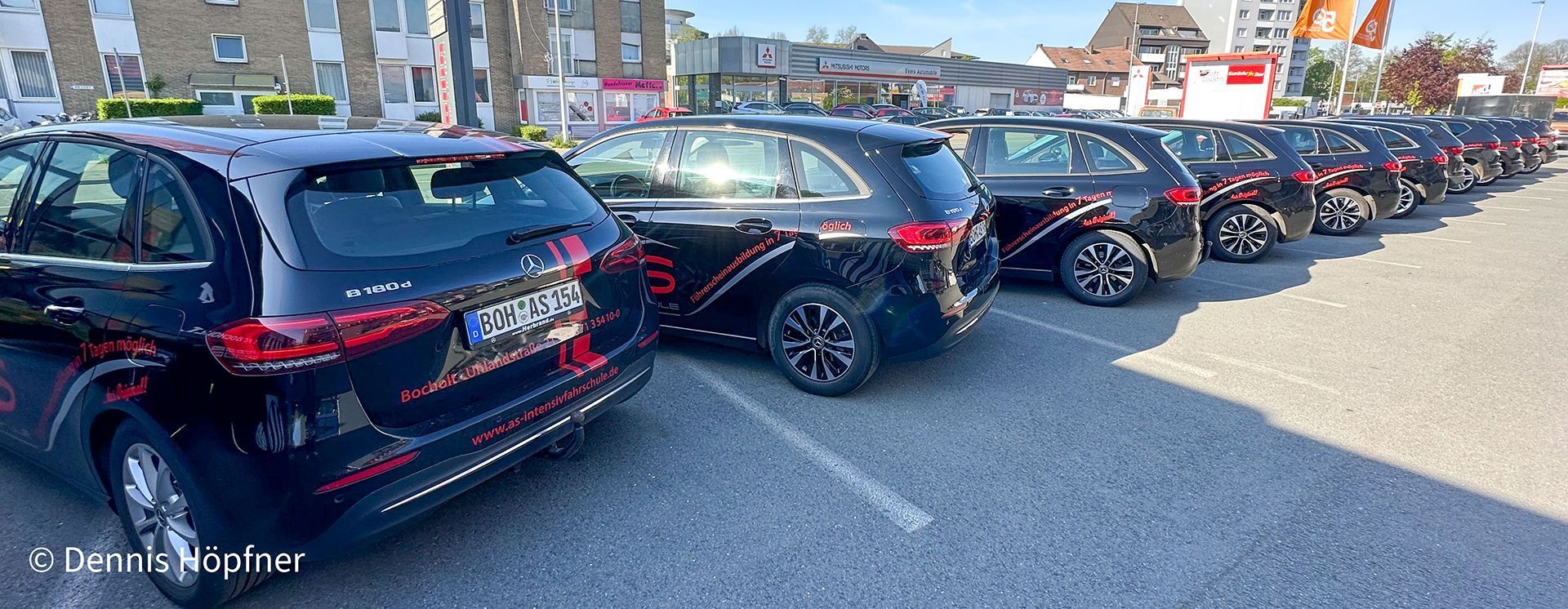 Auf einem Parkplatz steht eine Reihe schwarzer Autos.