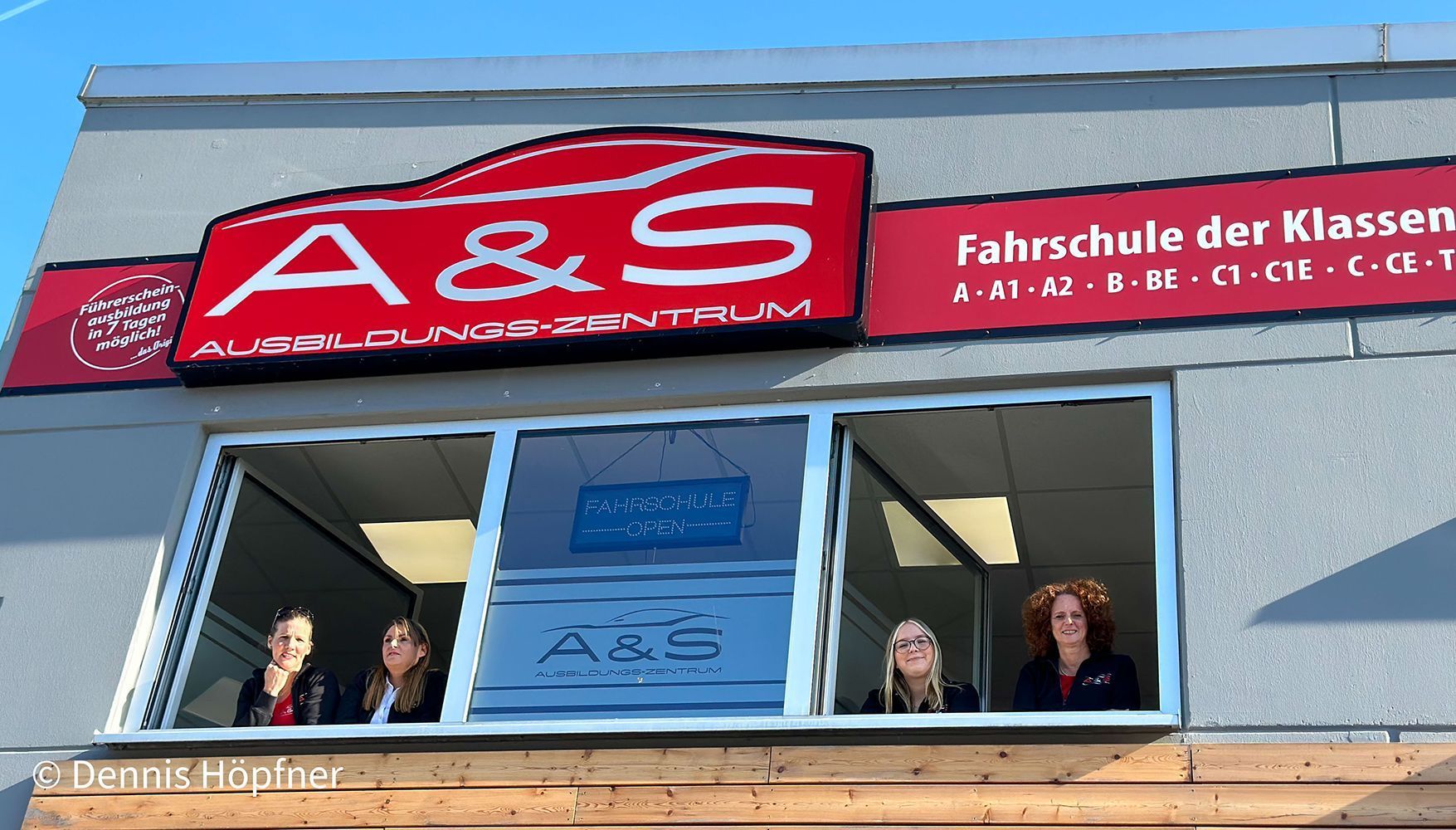 Eine Gruppe von Frauen steht vor einem Gebäude mit der Aufschrift „A & S“