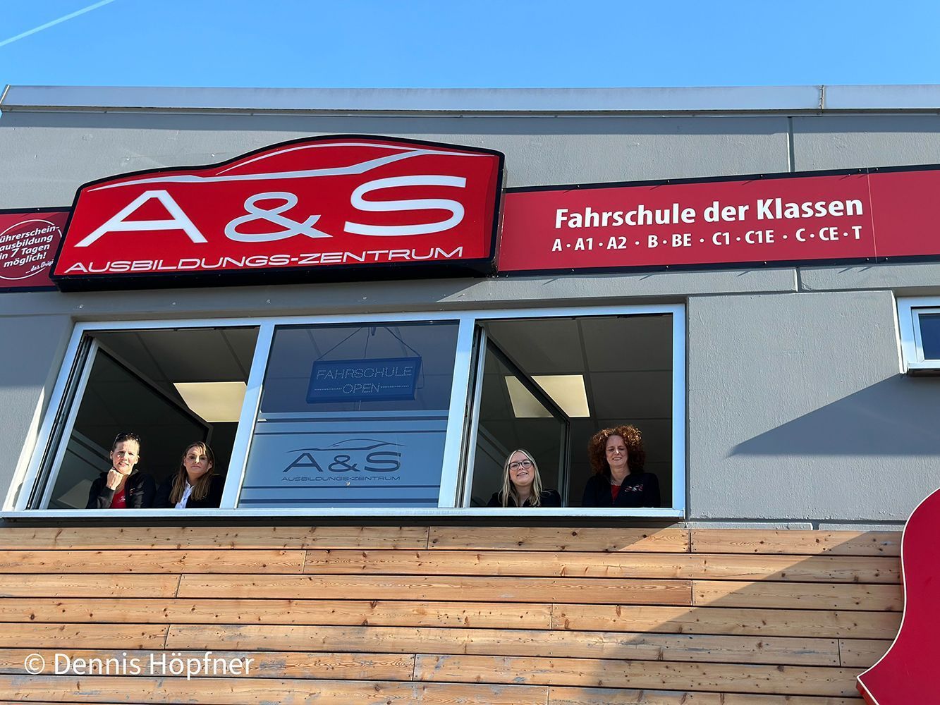 Eine Gruppe von Menschen steht vor einem Gebäude mit einem Schild mit der Aufschrift A & S