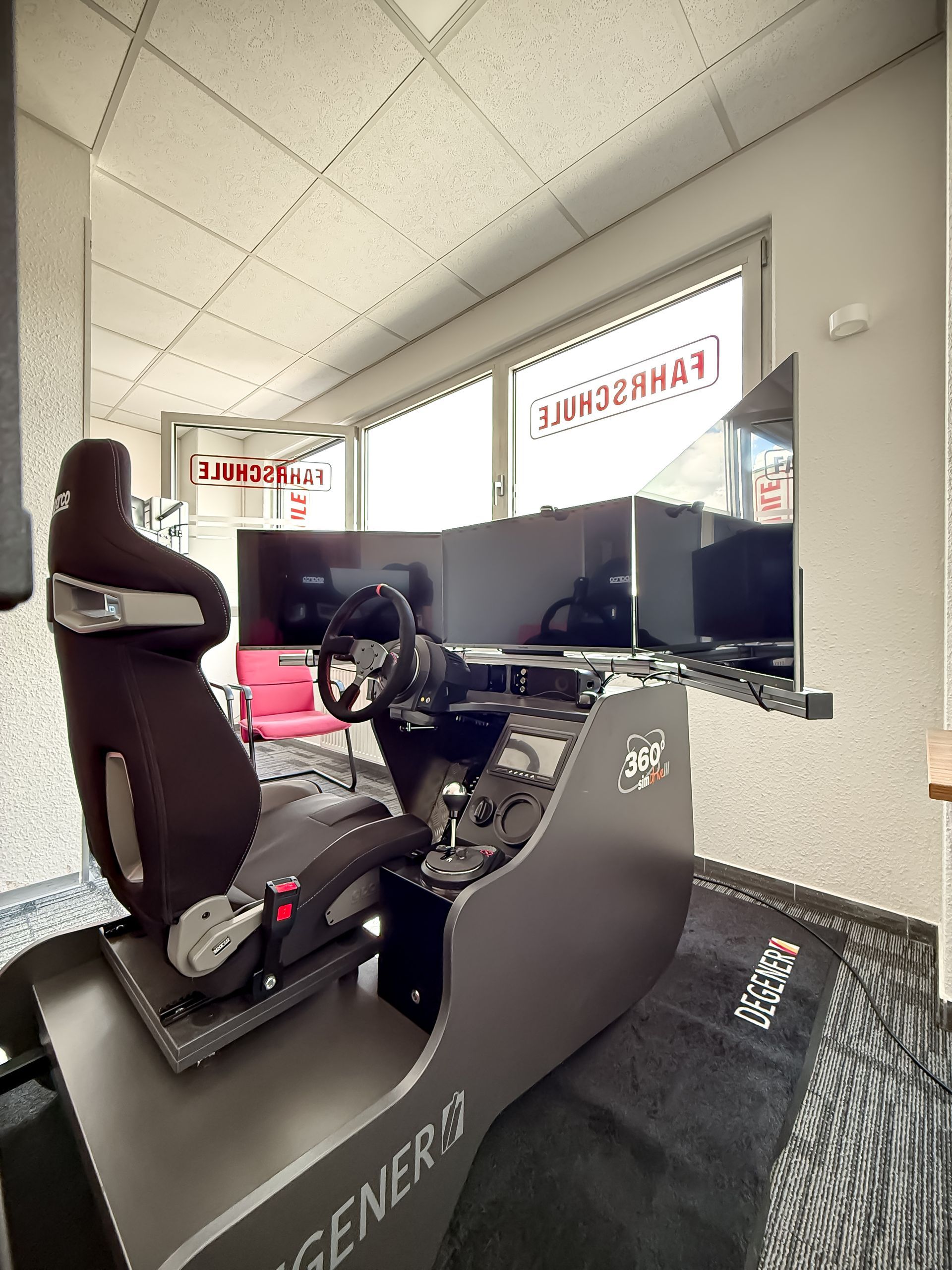 Rennsimulator mit schwarzem Sitz und drei Monitoren.
