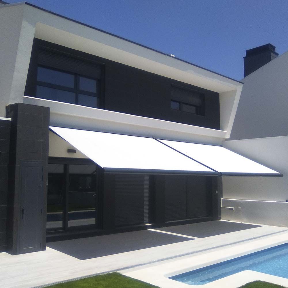 Una moderna casa de dos plantas con un toldo retráctil blanco que se extiende sobre un patio junto a una piscina.