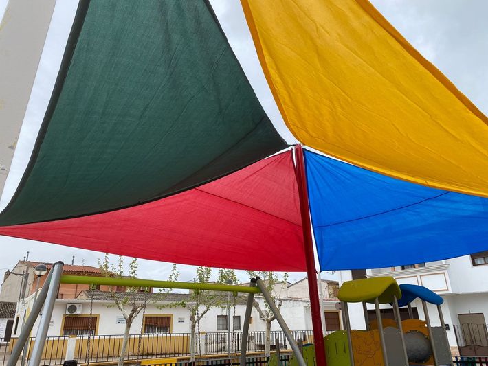 Un escaparate con grandes ventanales, un marco gris oscuro, un toldo a rayas beige y granate.