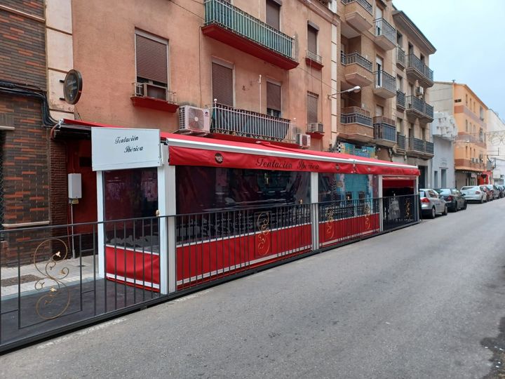 Un moderno balcón acristalado con vistas a una ciudad con árboles y edificios al fondo.