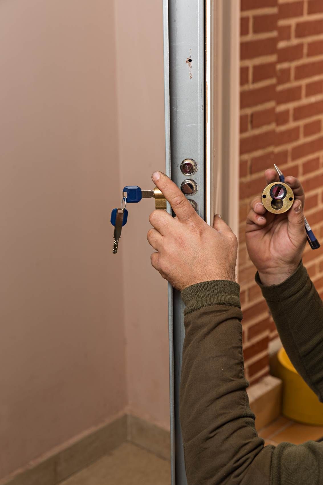 Mains tenant une serrure et une clé contre un cadre de porte lors de l'installation d'une serrure