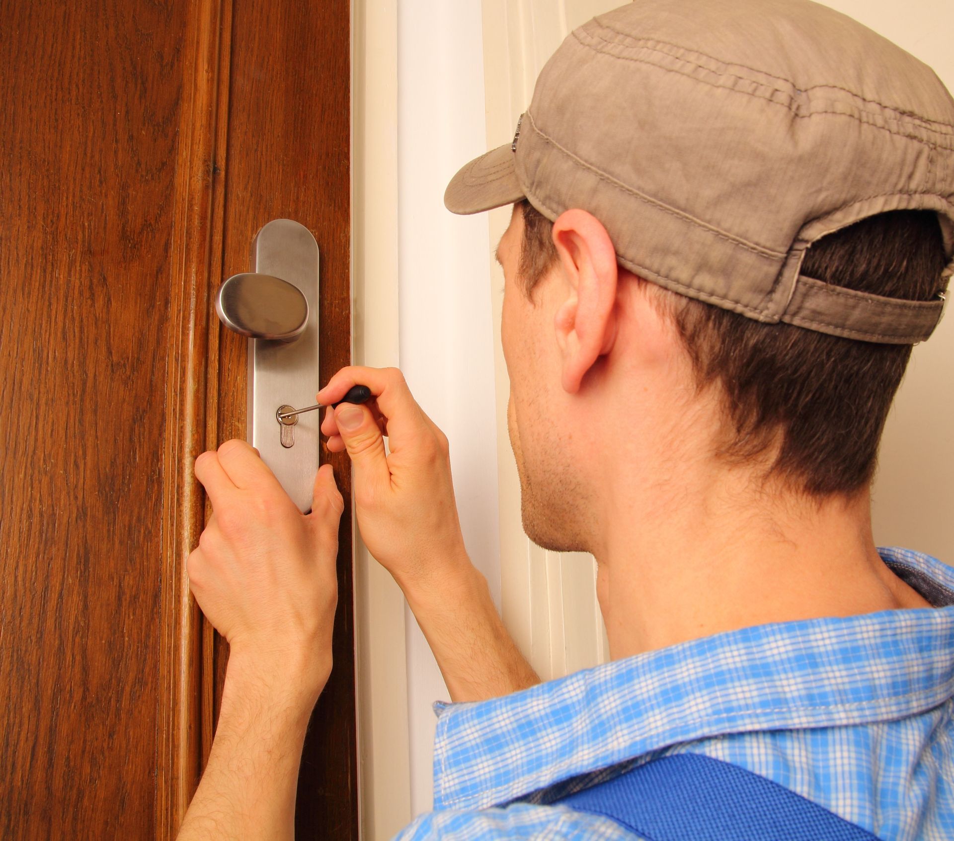 Une personne utilise une clé dans une serrure pour ouvrir une porte en bois.
