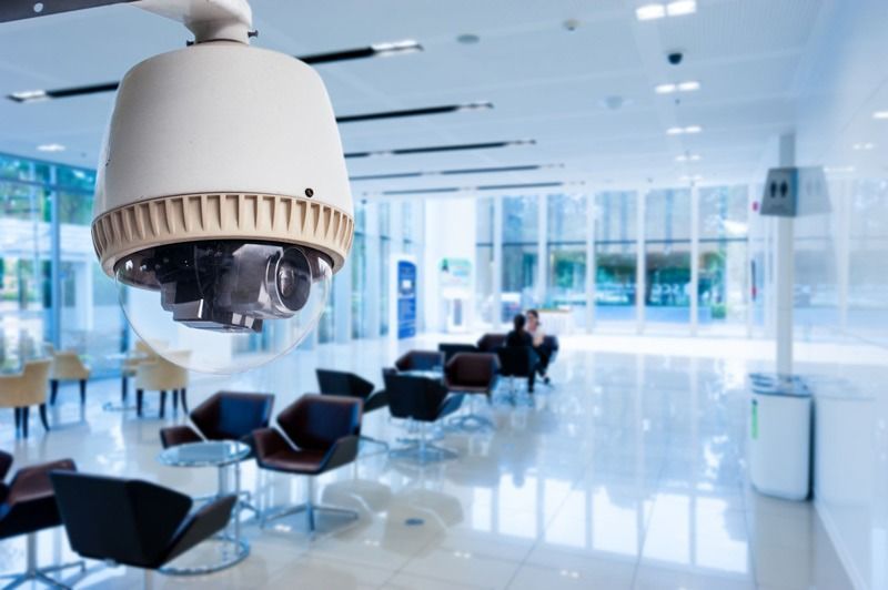 Cámara de seguridad en un moderno lobby con zonas de estar y grandes ventanales.