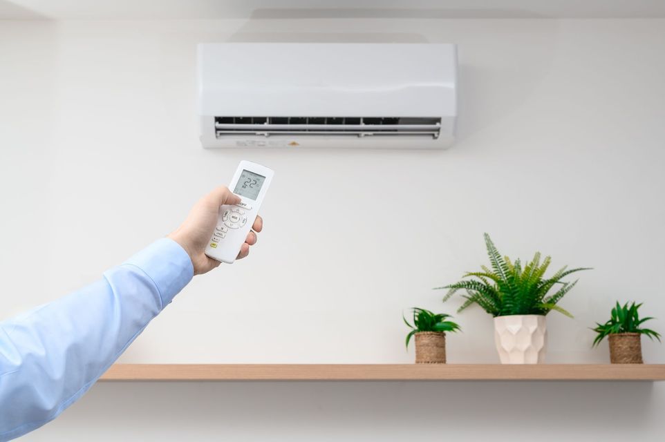 Une personne utilise la télécommande du climatiseur et la pointe vers le climatiseur