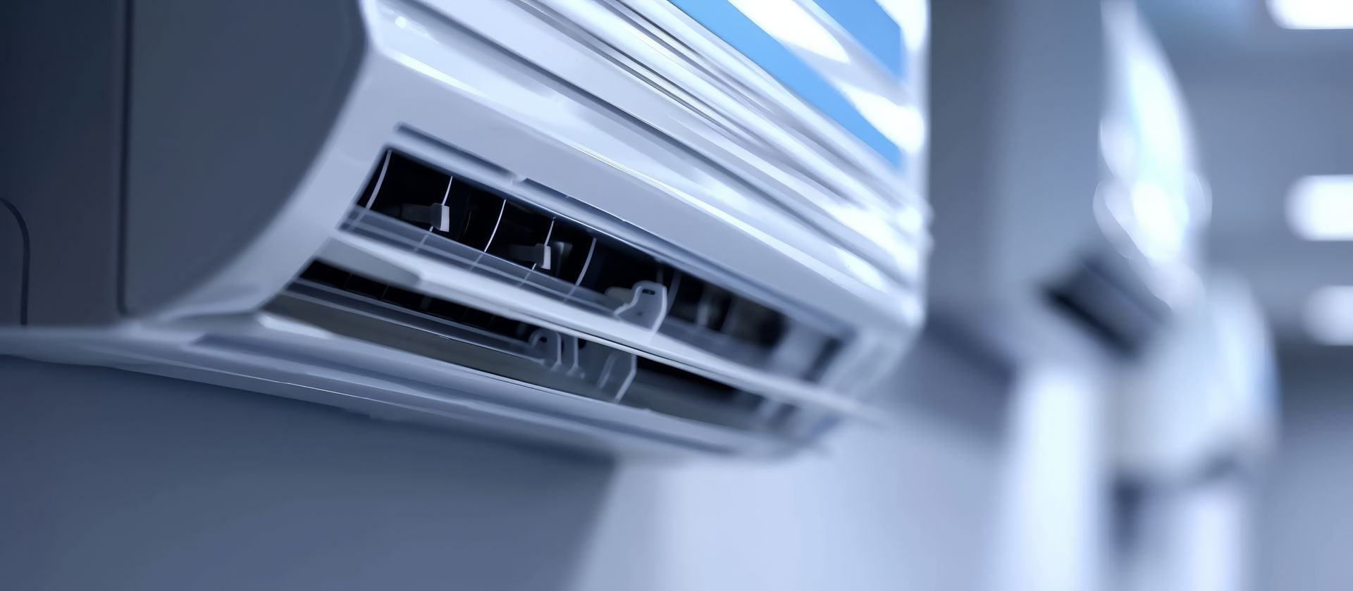 Gros plan sur un climatiseur blanc. Un autre appareil flou apparaît à l'arrière-plan.